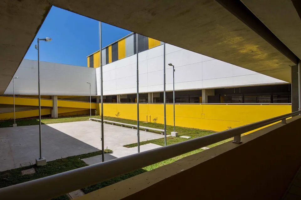 Uma vista de um prédio amarelo e branco de uma varanda.