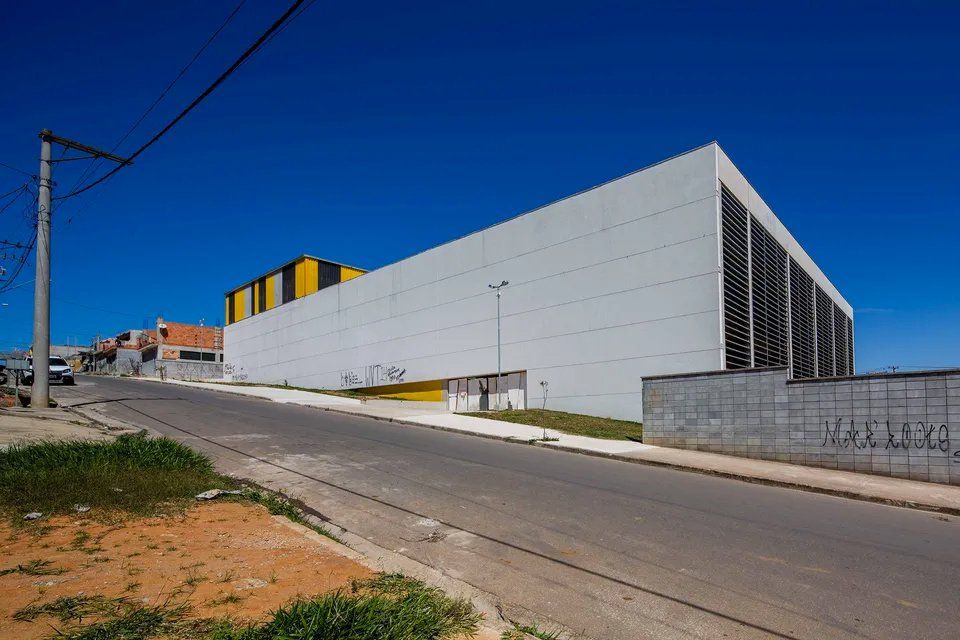 Um grande edifício branco está situado no topo de uma colina próximo a uma estrada.
