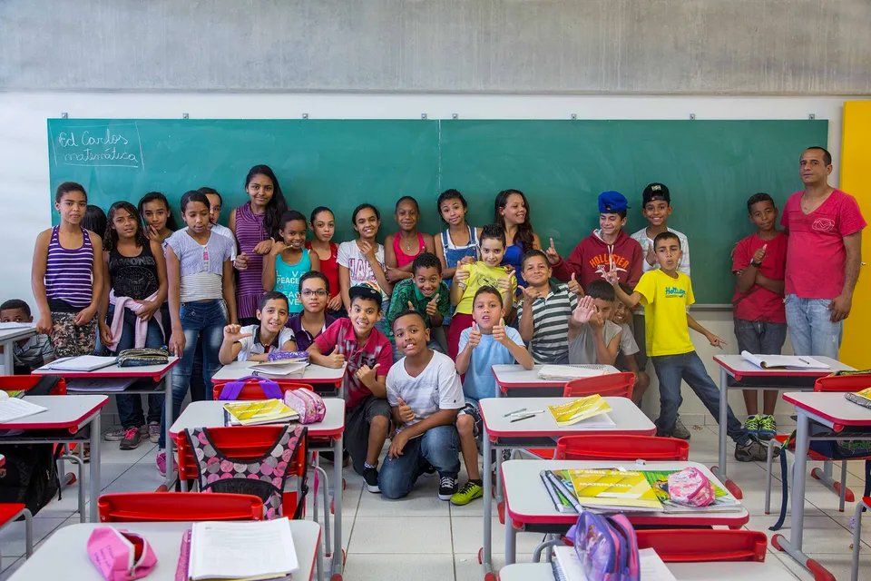 Um grupo de crianças posando para uma foto em uma sala de aula