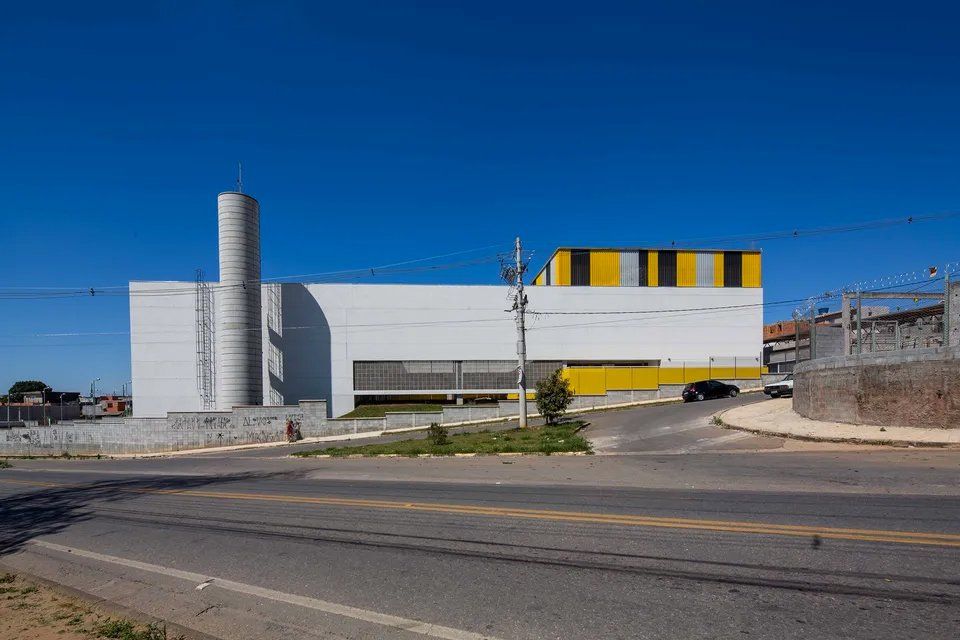 Um grande edifício branco com telhado amarelo está situado próximo a uma estrada.