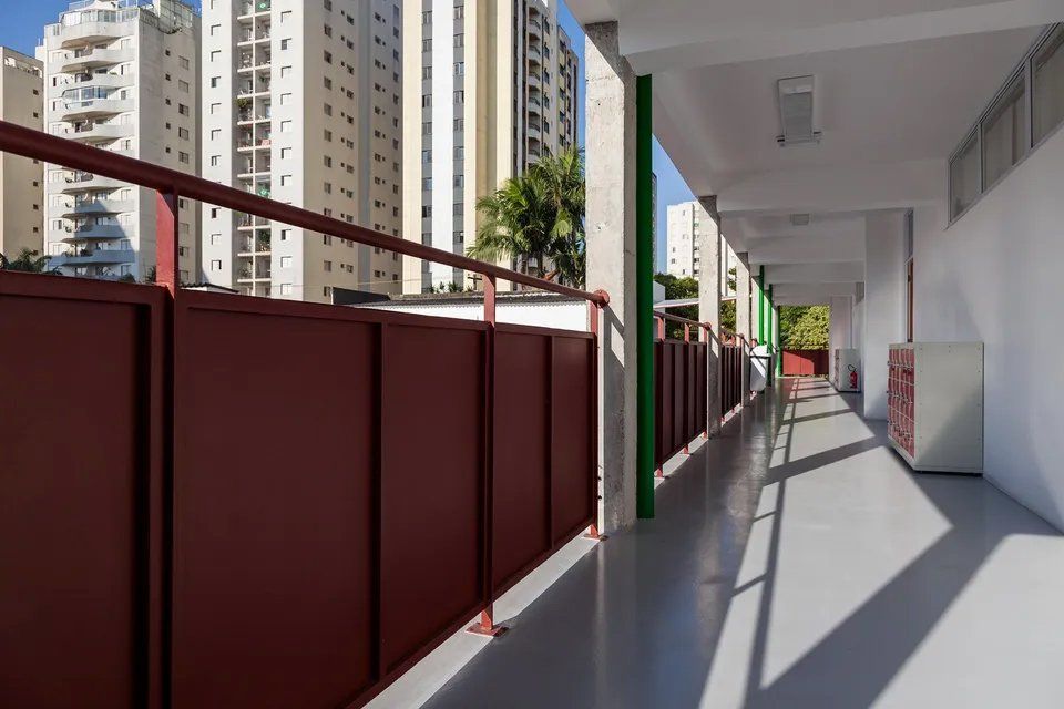 Um longo corredor em um prédio com grade vermelha