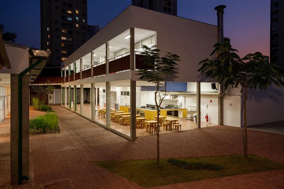Um grande edifício com mesas e cadeiras na frente dele