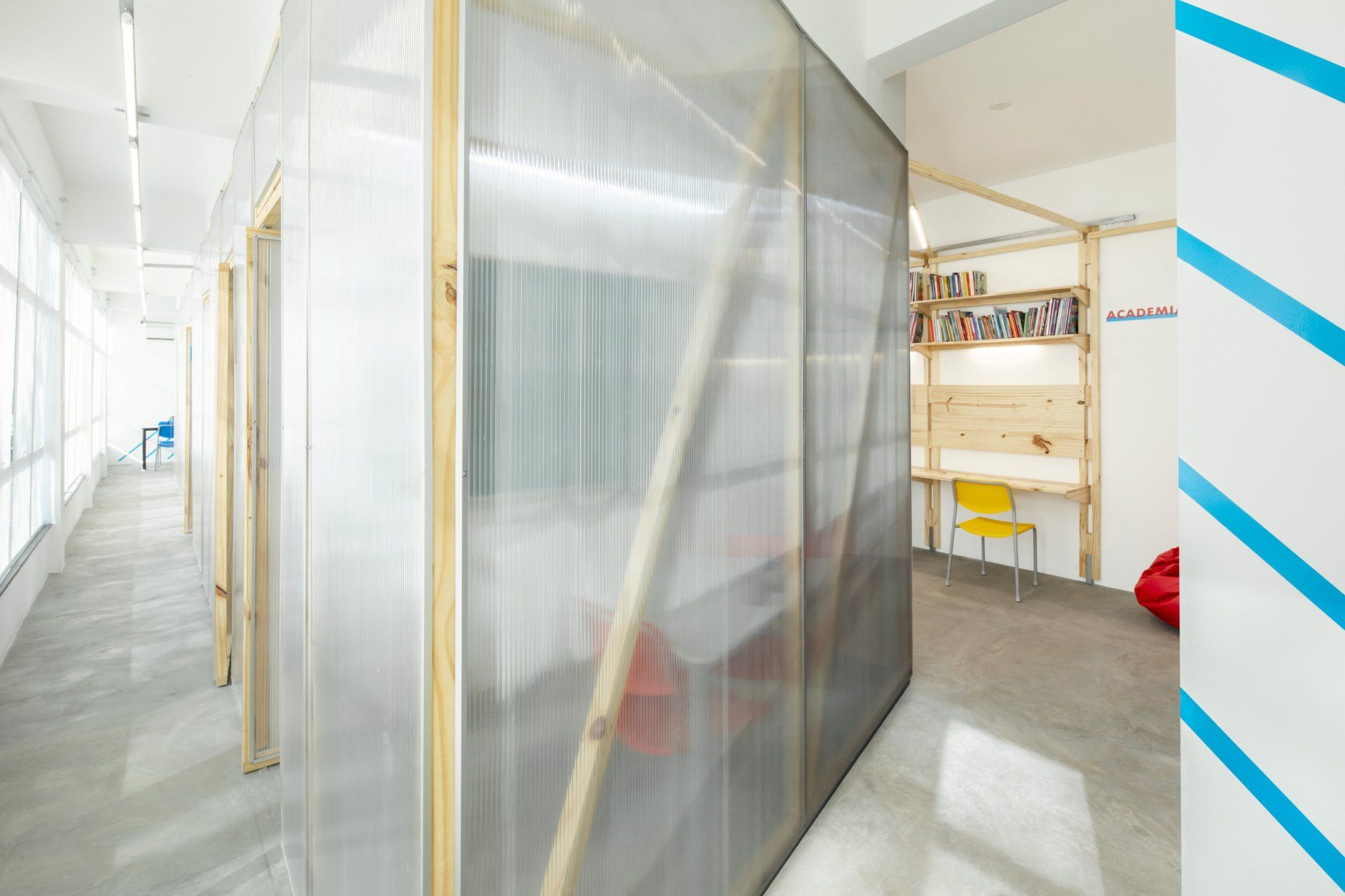 Um corredor com uma parede de plástico transparente entre dois quartos.
