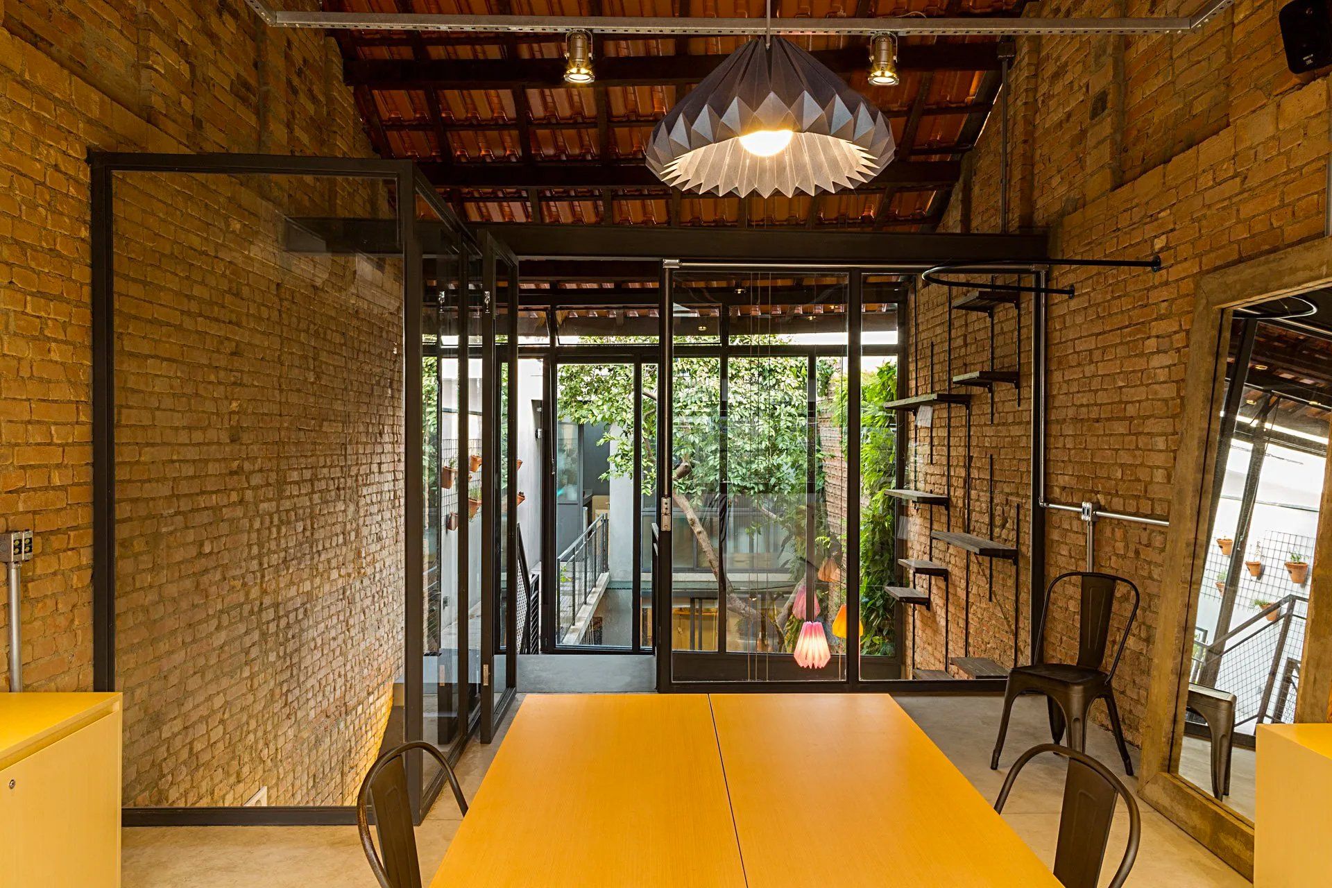 Uma sala com mesa e cadeiras amarelas e uma parede de tijolos.