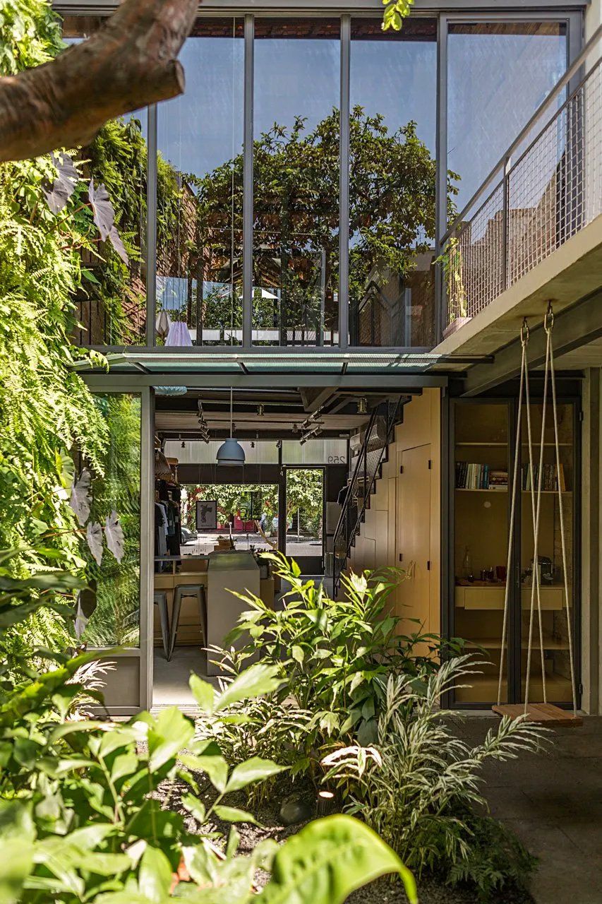 Uma casa com muitas janelas é cercada por árvores e plantas.