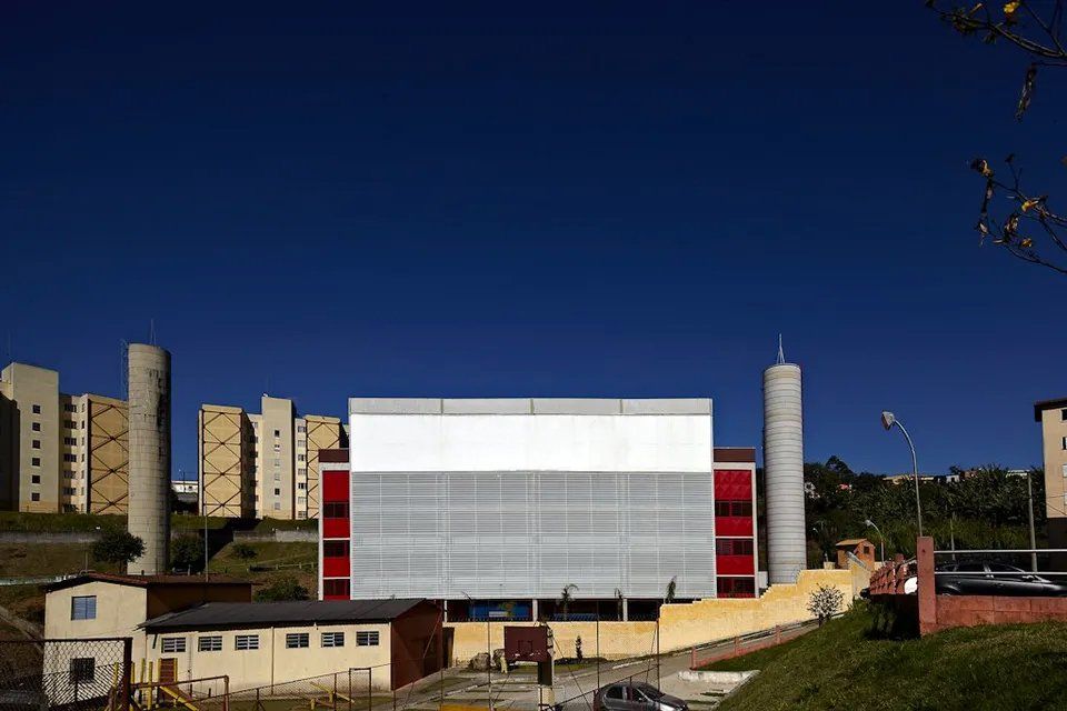 Um grande edifício com telhado branco fica no meio de uma cidade.