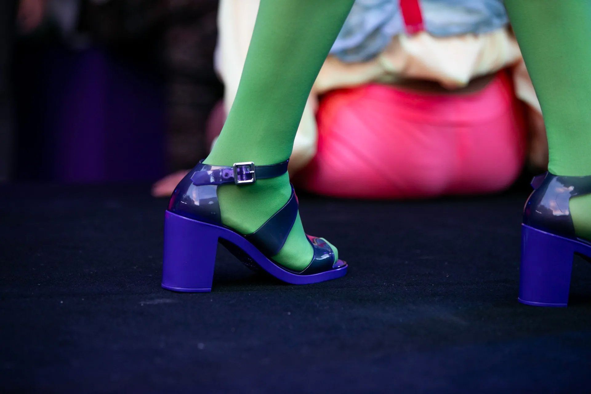 Uma mulher vestindo meia-calça verde e sapatos roxos.