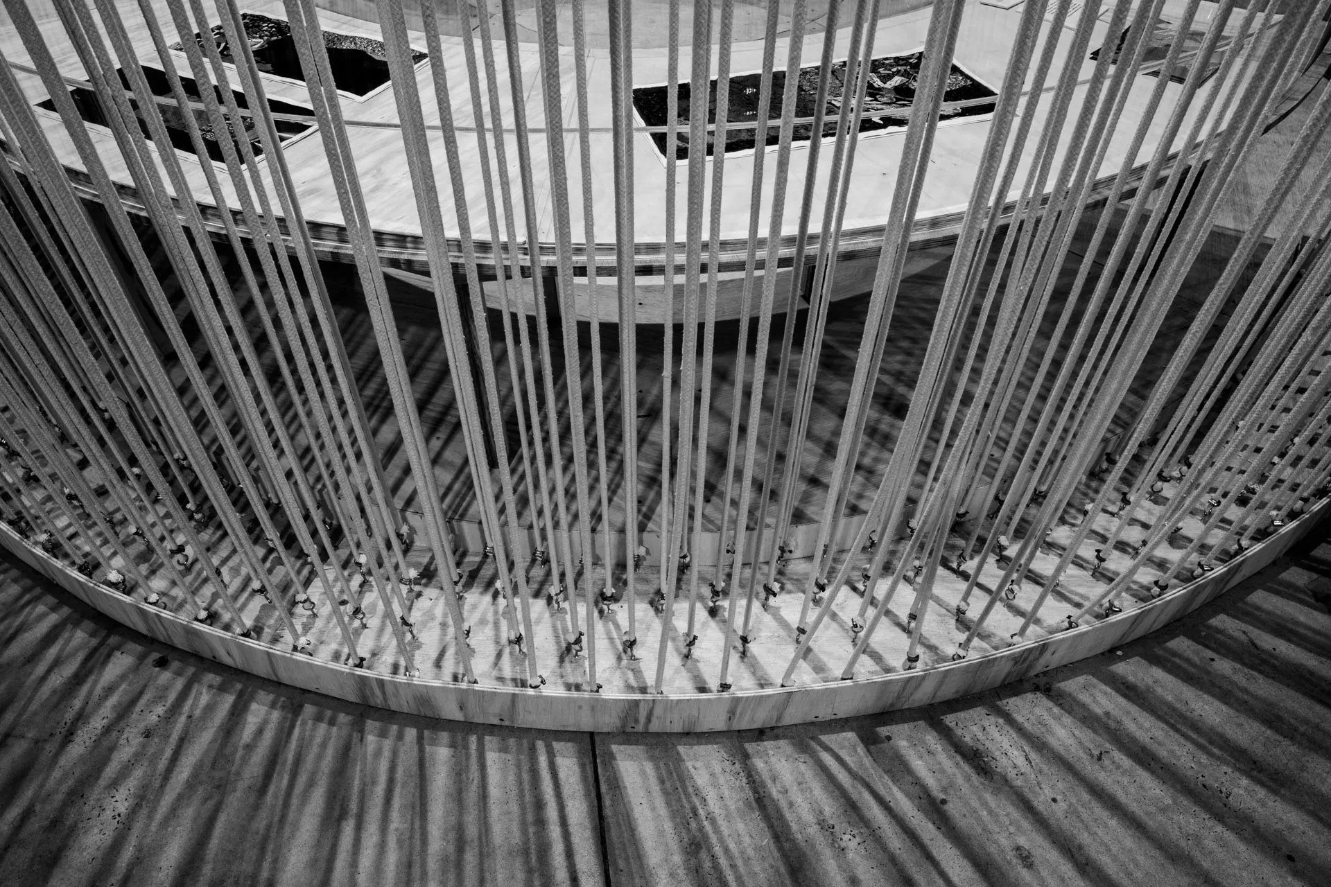Uma foto em preto e branco de uma gaiola circular com uma mesa ao fundo.