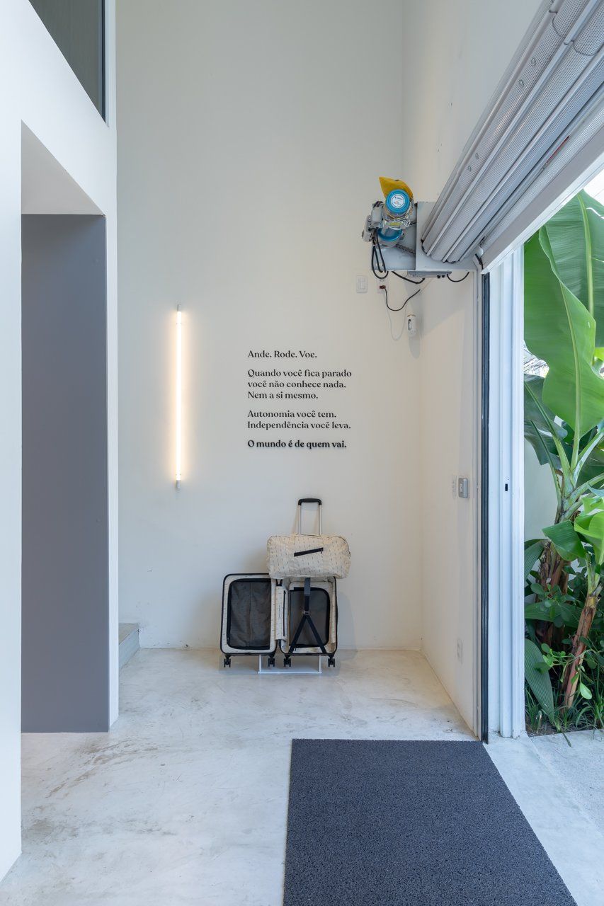 Um quarto branco com uma mala e uma placa na parede