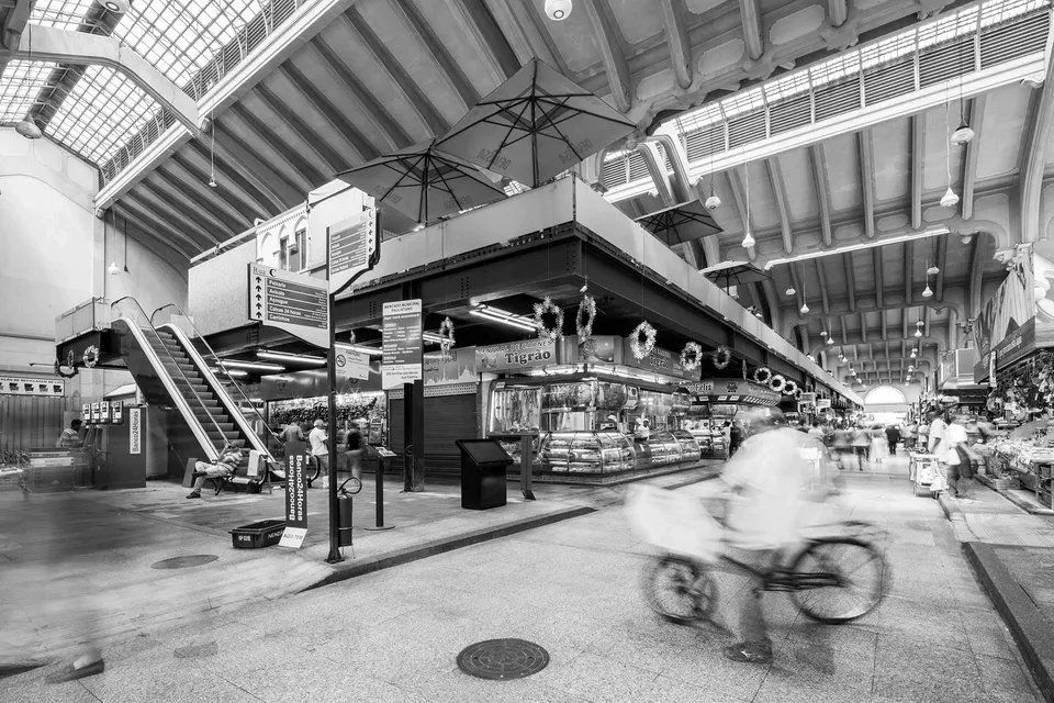 Uma foto em preto e branco de um mercado com uma pessoa andando de bicicleta.
