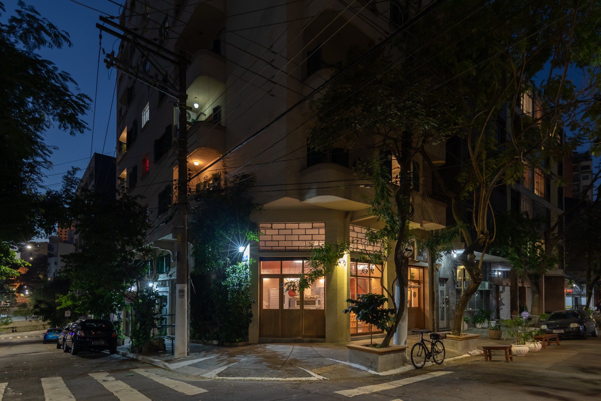 Um prédio com uma bicicleta estacionada em frente à noite.