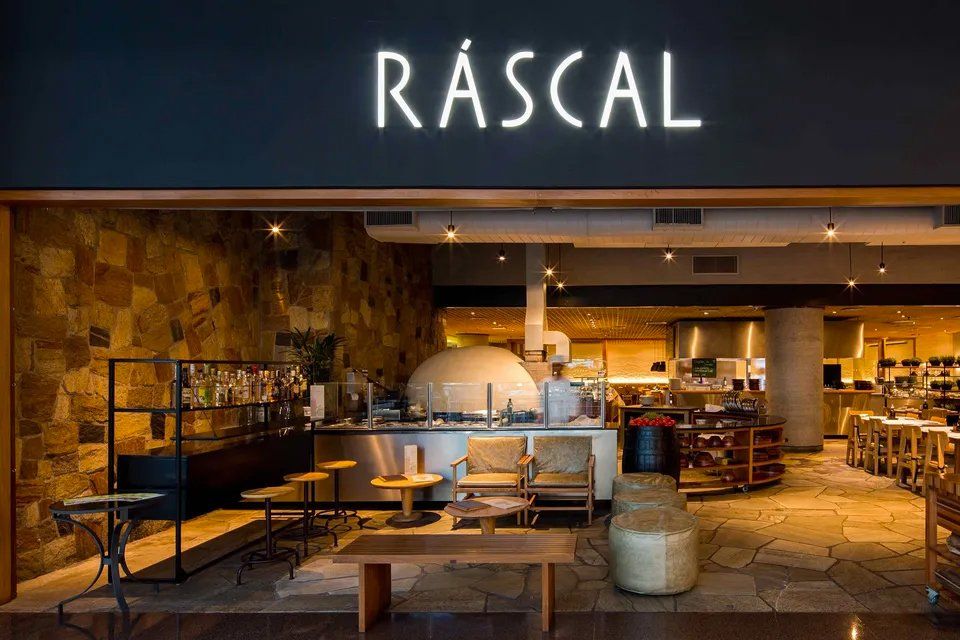 O interior de um restaurante com mesas e cadeiras e forno de pizza.