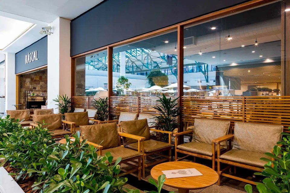 Um restaurante com muitas cadeiras e mesas em frente a uma grande janela.