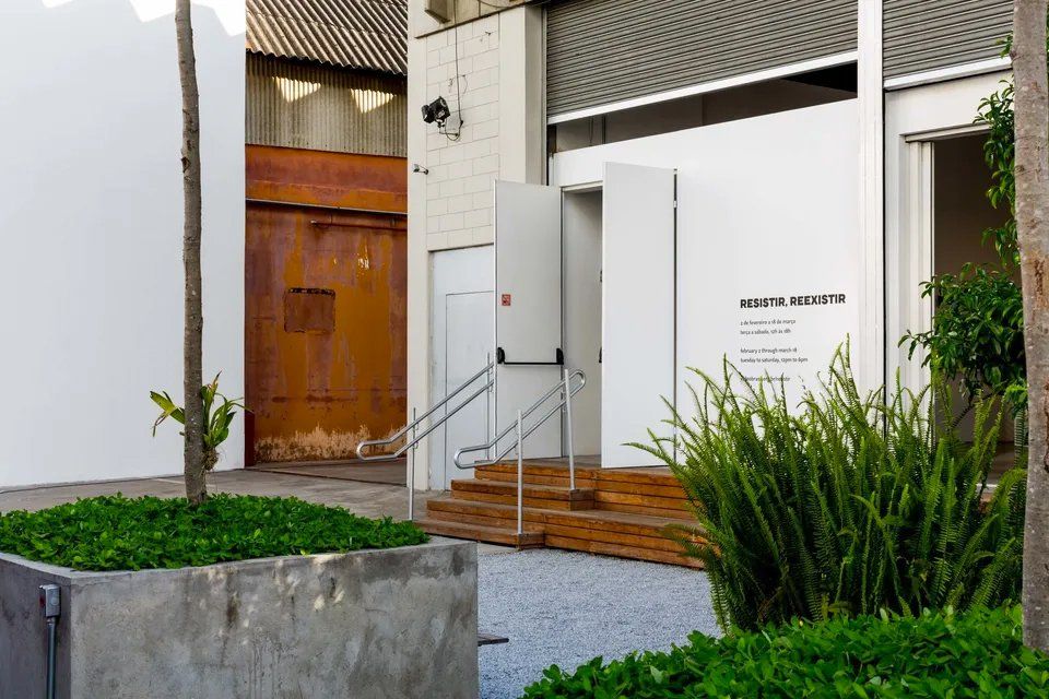 Um prédio branco com uma porta de madeira e escadas que levam até ele.