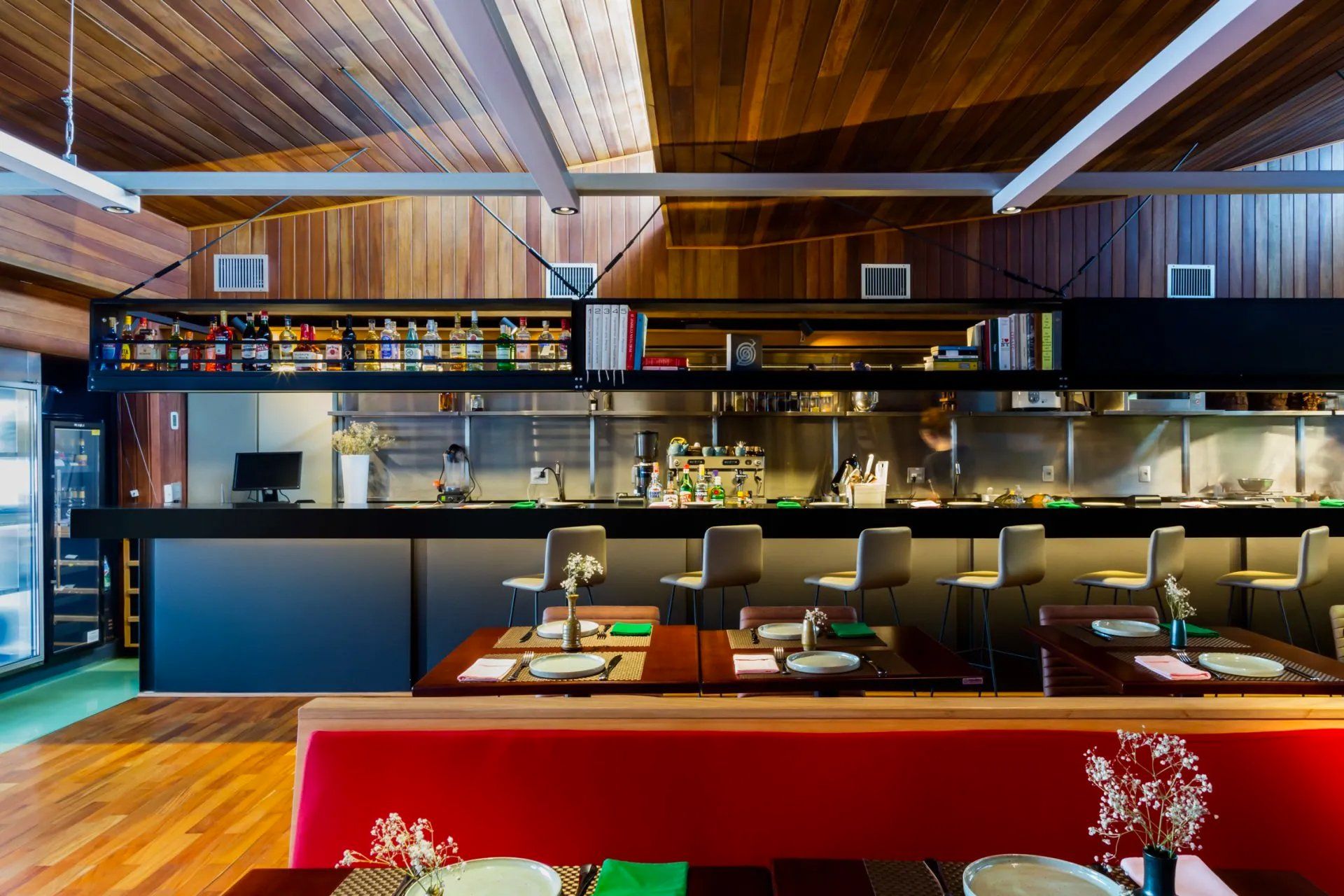 Um restaurante com mesas e cadeiras e uma cozinha ao fundo