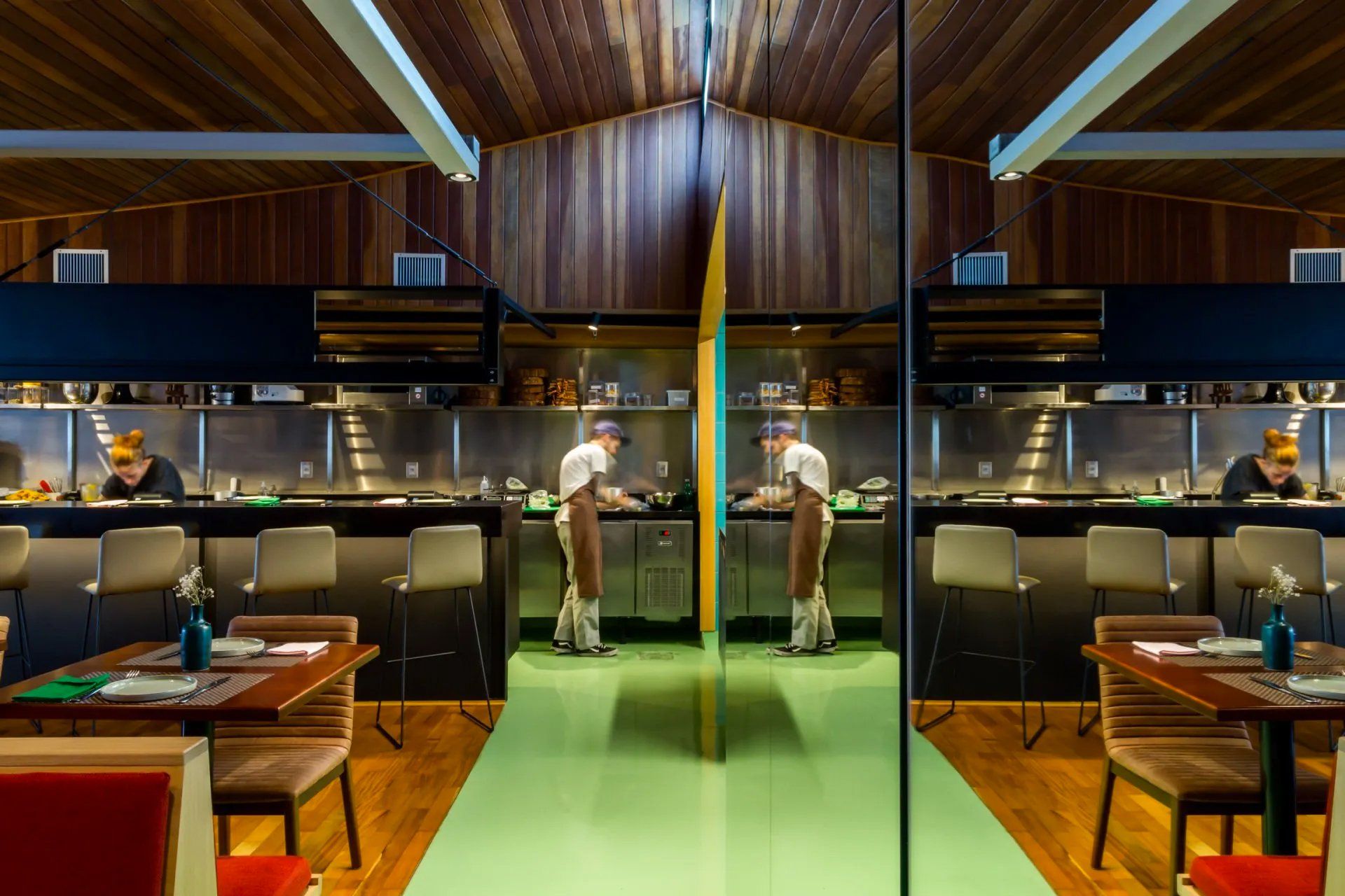 Um restaurante com mesas e cadeiras e um chef na cozinha