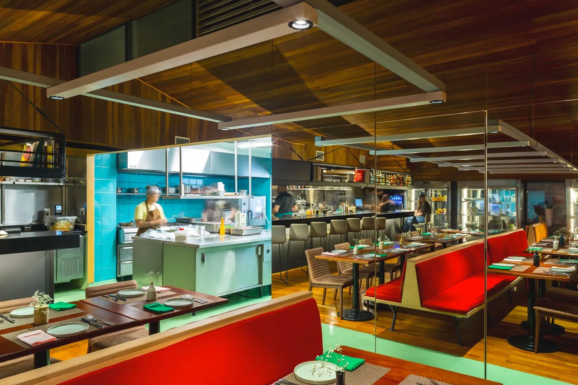 Um restaurante com mesas e cadeiras e uma cozinha ao fundo.