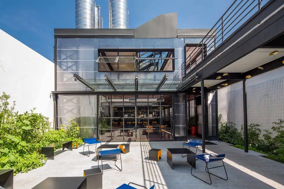 Um grande edifício com muitas janelas e mesas e cadeiras na frente dele.
