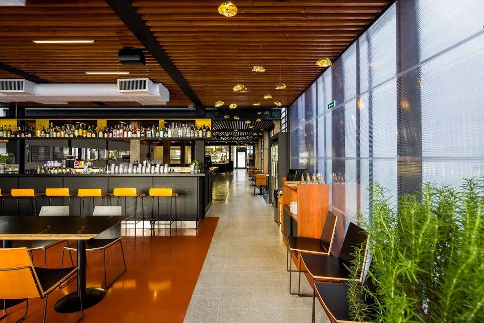 Um restaurante com mesas e cadeiras e um bar.