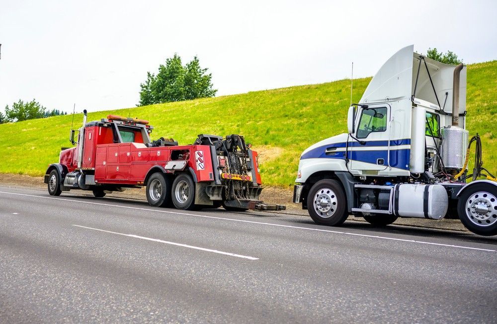 A Tow Truck is Towing a Semi Truck on the Side of the Road — Kenny's Towing in Jensen, QLD