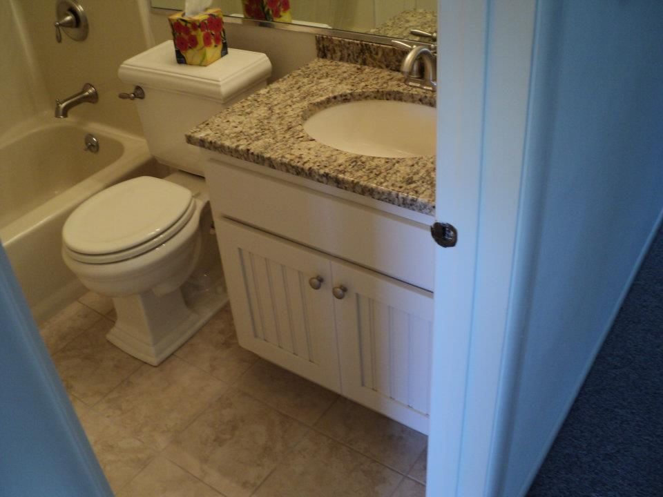 Small bathroom with toilet, sink vanity, bathtub, and beige tile floor
