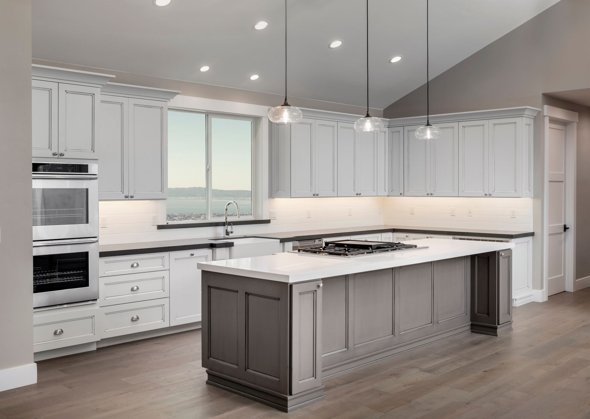 Bright modern white kitchen with large island, pendant lights, and built-in appliances
