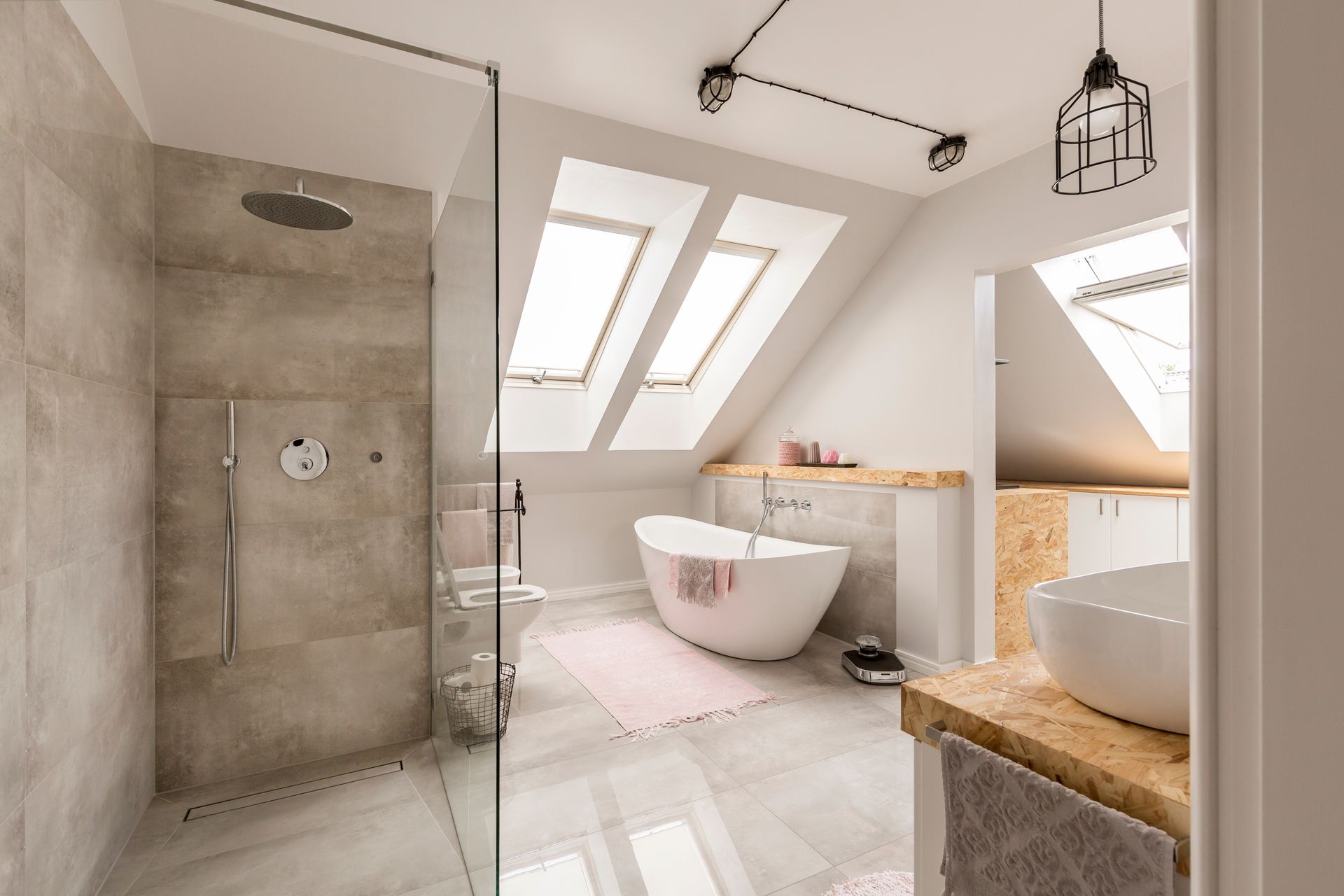 Modern attic bathroom with skylights, glass shower, freestanding tub, and white tile floor