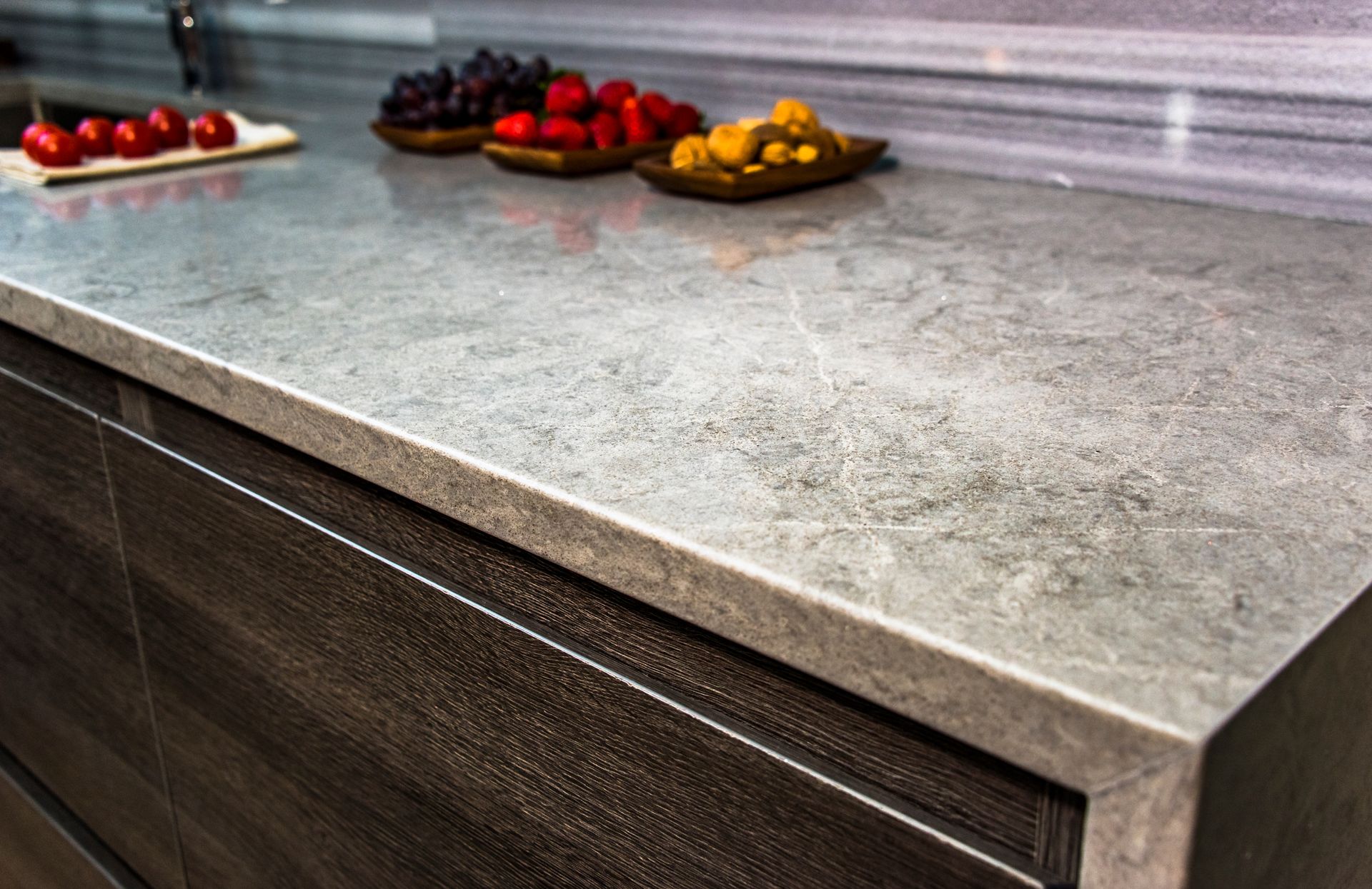 Modern kitchen countertop with three trays of assorted berries on the back edge