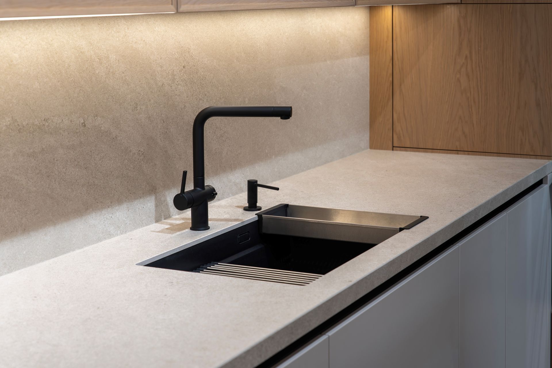 Modern kitchen countertop with black faucet and built-in sink, lit by under-cabinet lighting Modern kitchen countertop with black faucet and built-in sink, lit by under-cabinet lighting
