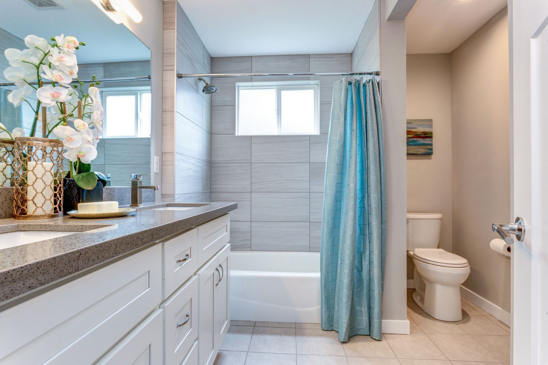 Bright bathroom with white vanity, tiled shower, bathtub, and turquoise curtain Bright bathroom with white vanity, tiled shower, bathtub, and turquoise curtain