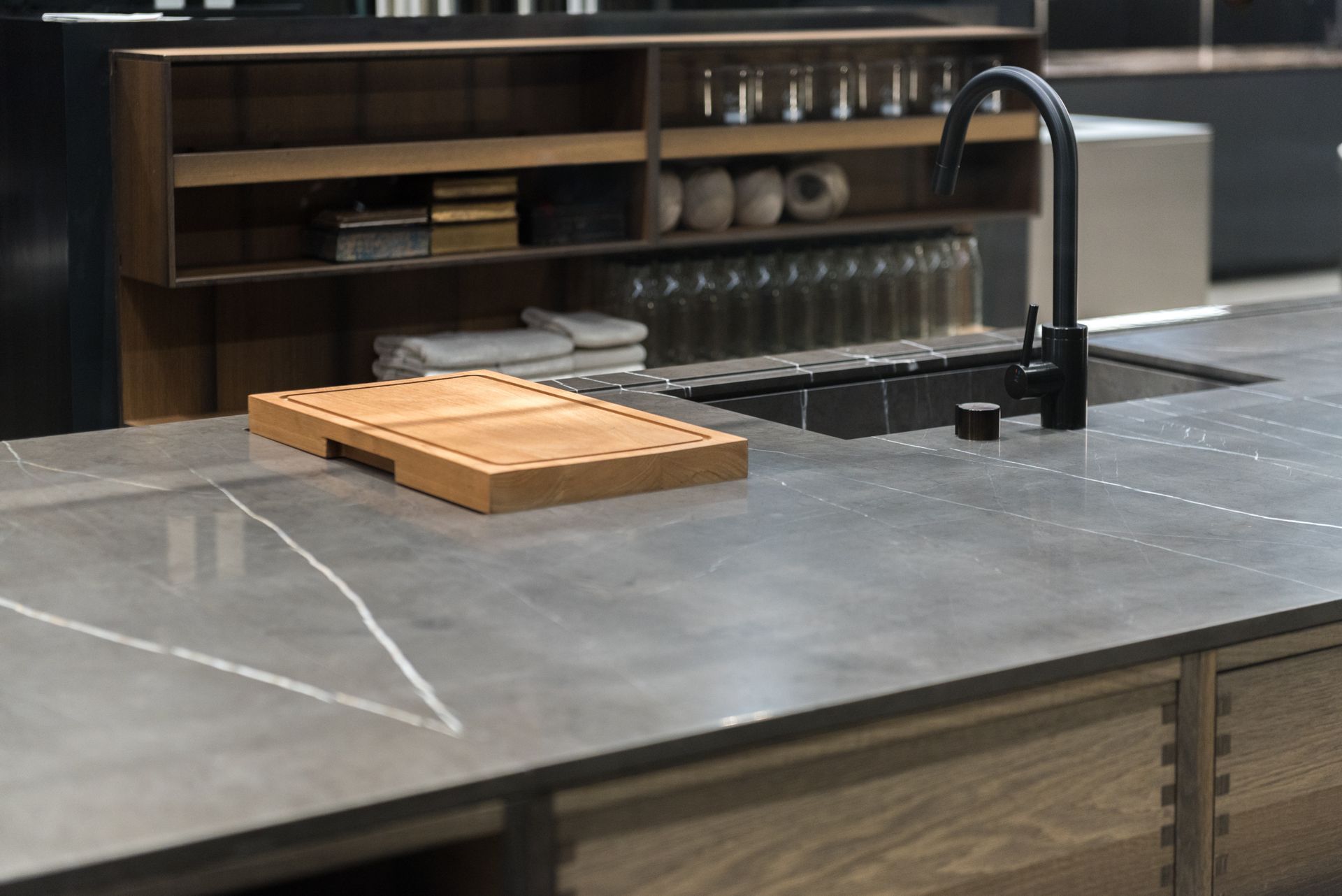 Modern kitchen island with black faucet and wooden cutting board on a gray countertop