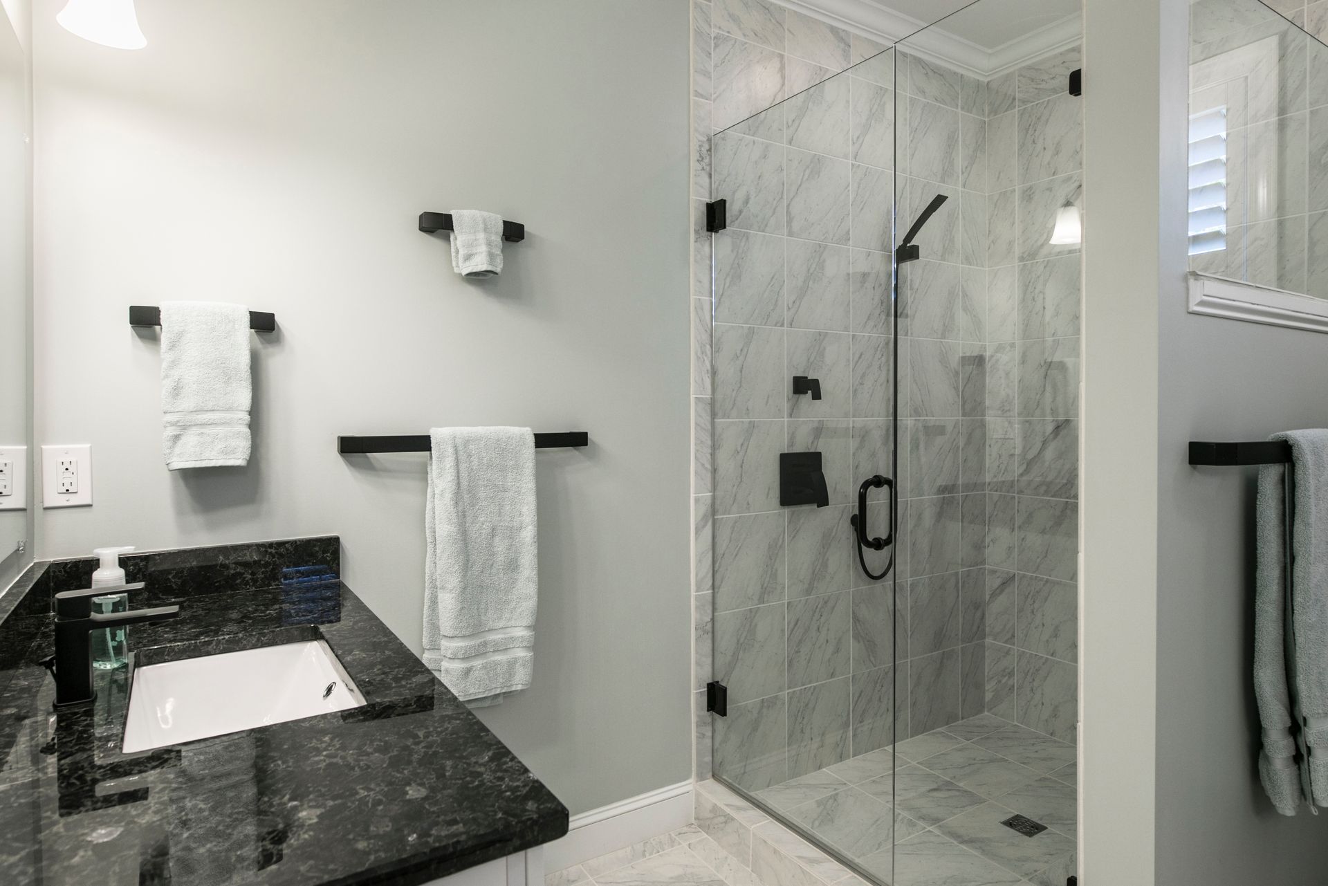 Modern bathroom with black vanity, white walls, and glass shower enclosure