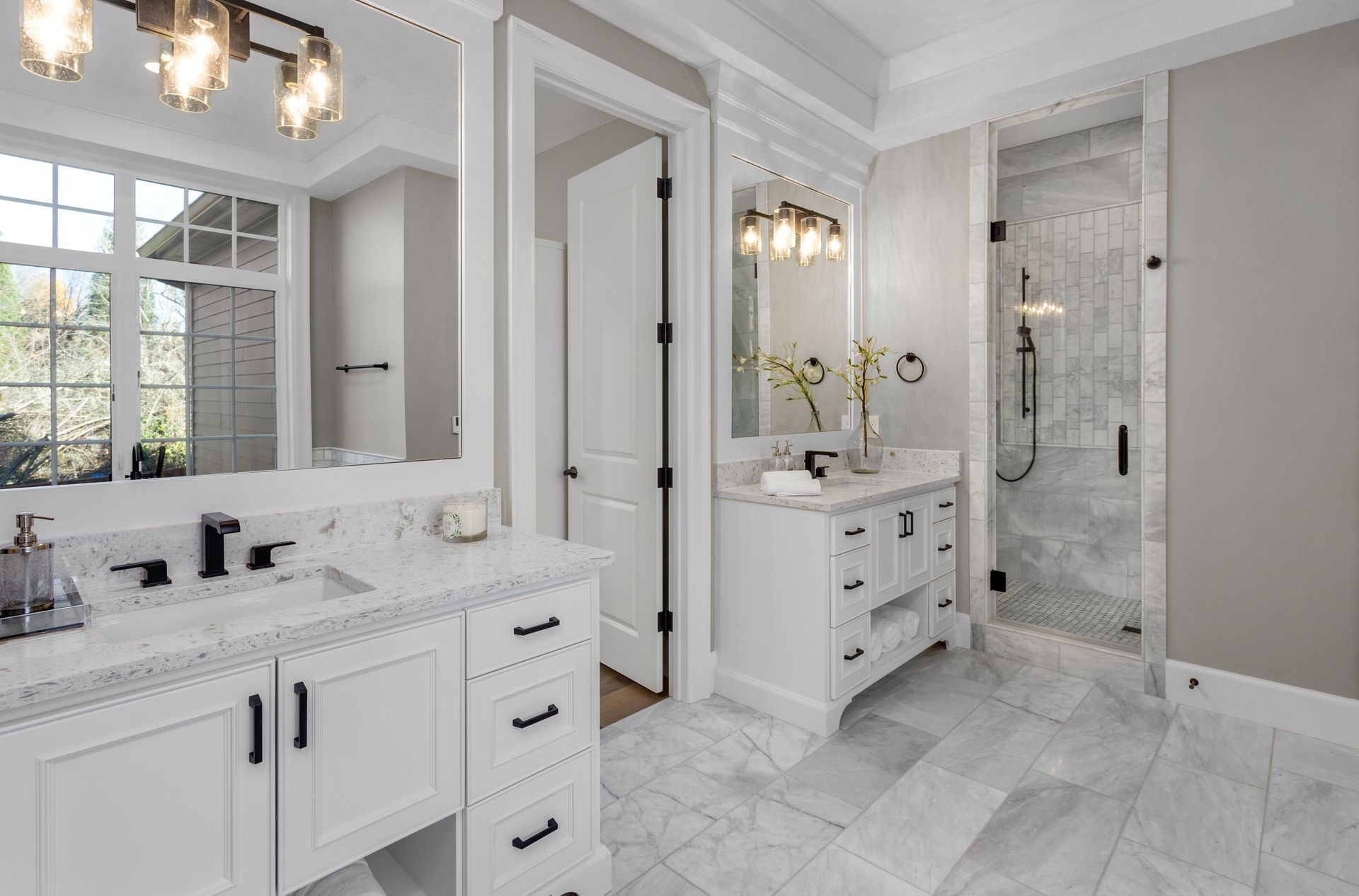 Bright white luxury bathroom with double vanity, large mirror, and glass shower in marble finishes