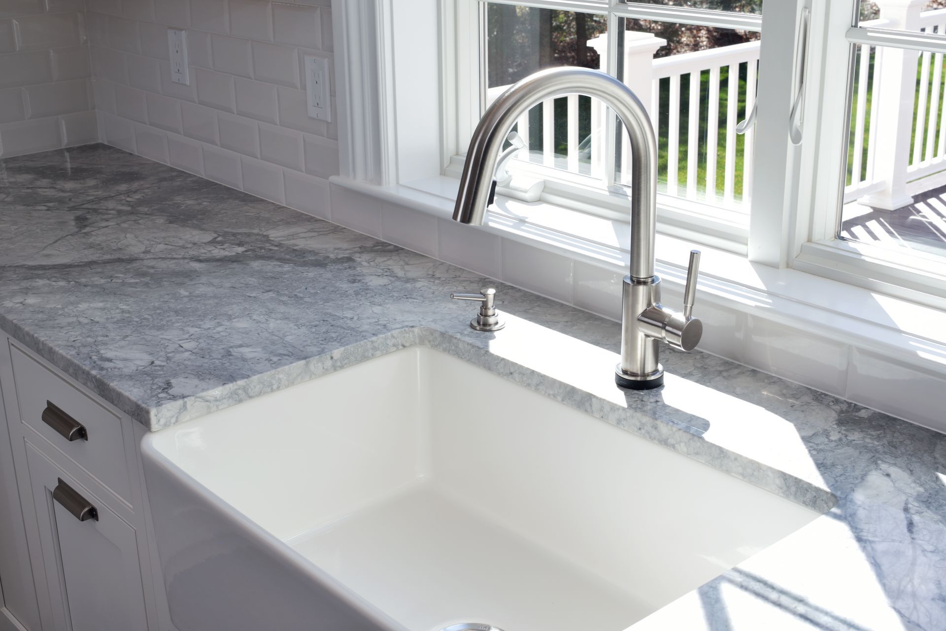 Modern kitchen sink with chrome faucet and gray countertop by a bright window