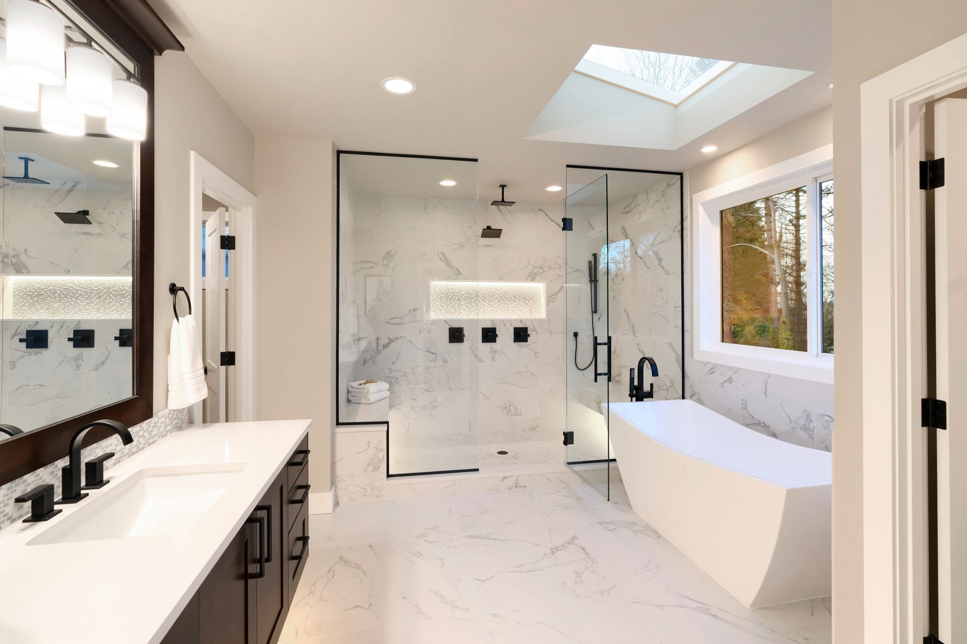 Bright modern bathroom with double vanity, freestanding tub, and marble-tiled shower area