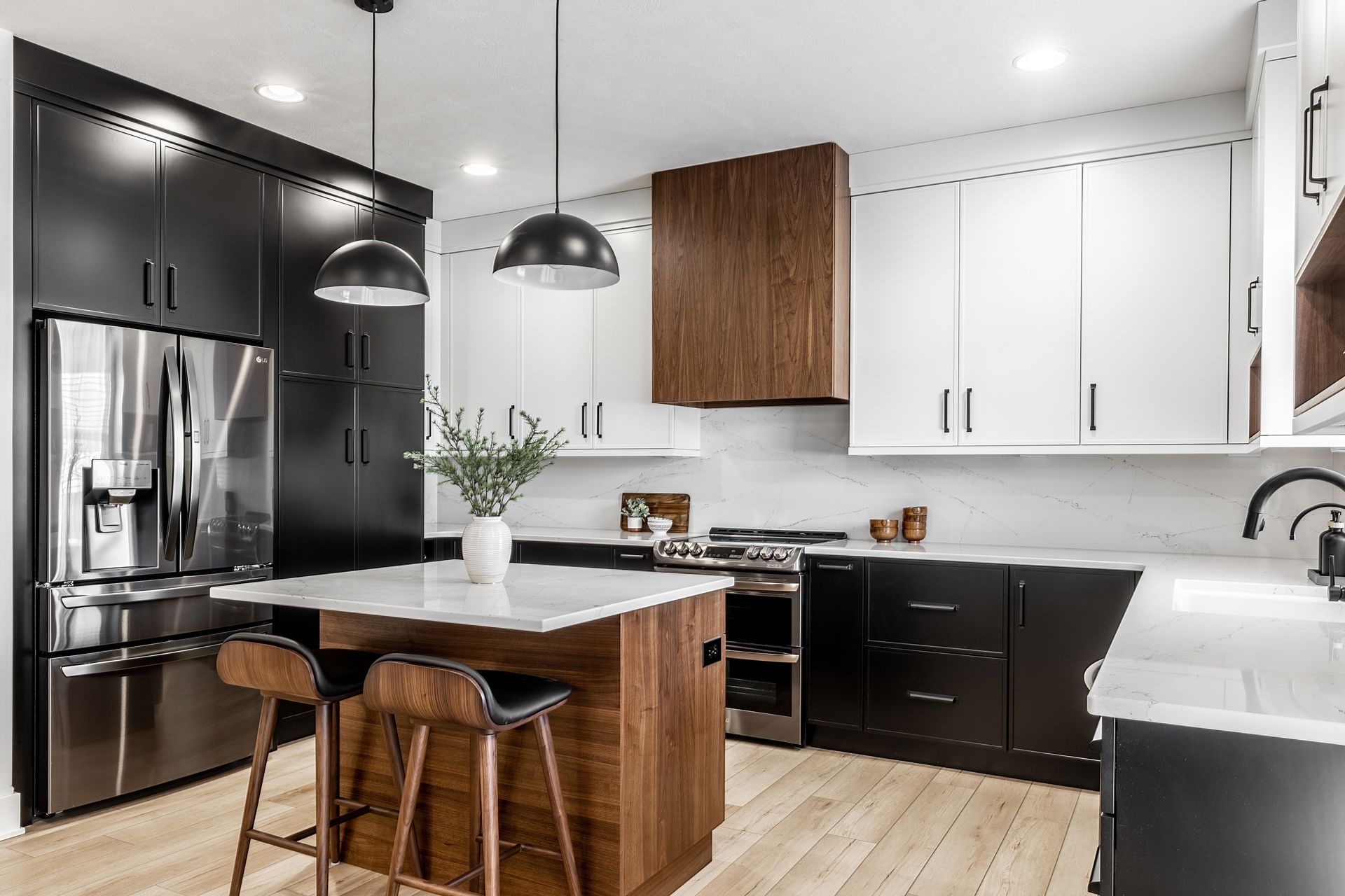 Modern kitchen with black and white cabinets, island, stainless steel appliances, and wood floors