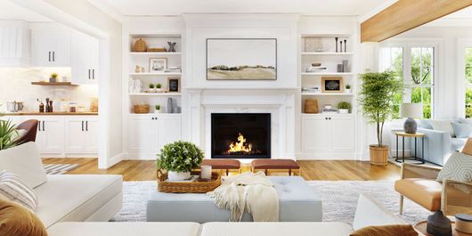 Bright, airy living room with a fireplace, built-in shelves, beige seating, and large windows