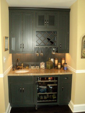 Built-in dark green bar cabinet with wine rack and countertop in a recessed alcove