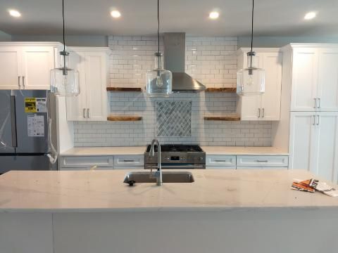 Modern kitchen with white cabinets, island, and a stainless steel refrigerator.