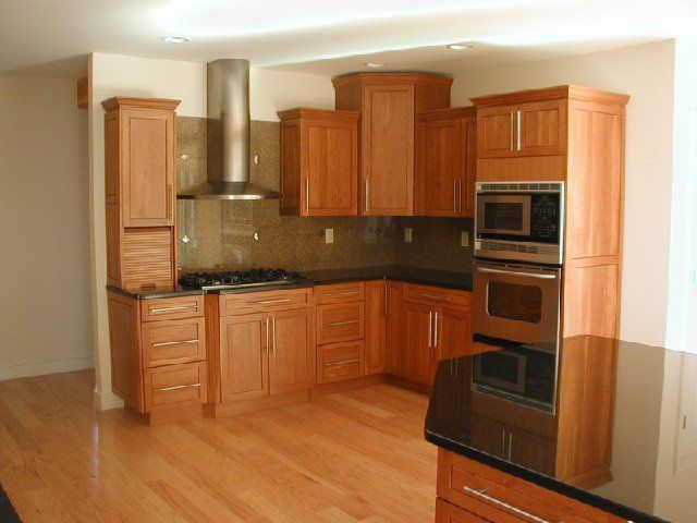 Modern kitchen with light wood cabinets, stainless appliances, and hardwood floors