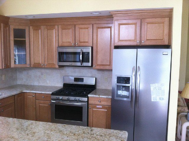Modern kitchen with wood cabinets, stainless steel appliances, and a granite countertop