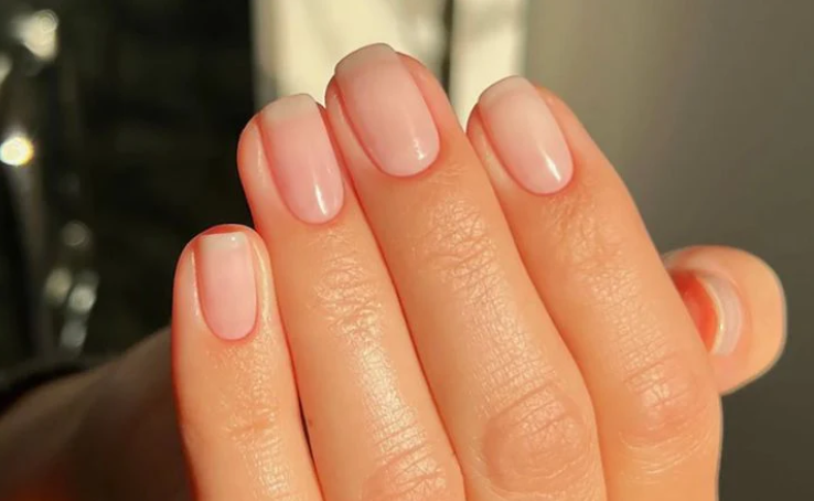 Close-up of hand with glossy pale pink manicured nails