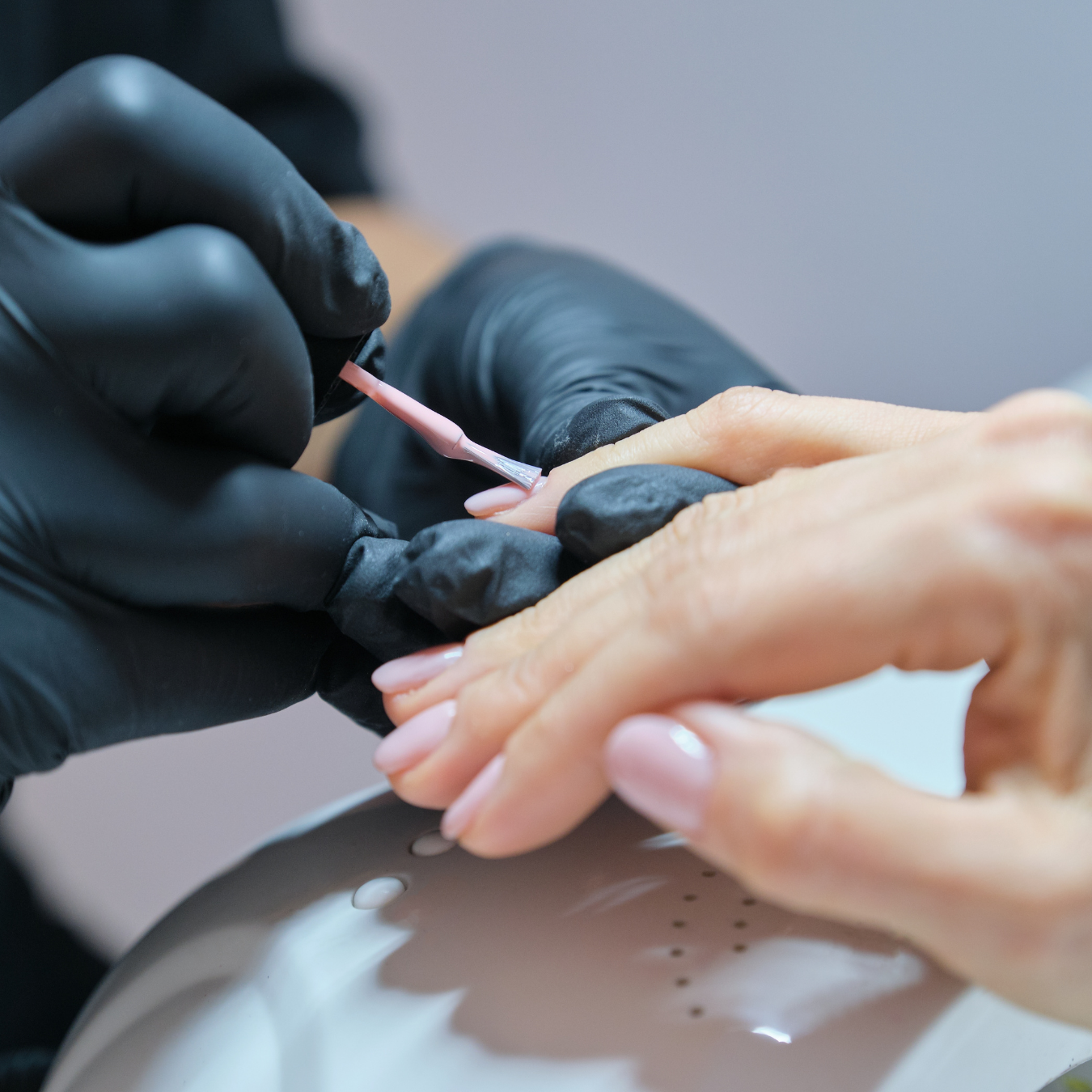 Hands with French manicure and pink glitter nail art resting together on a countertop