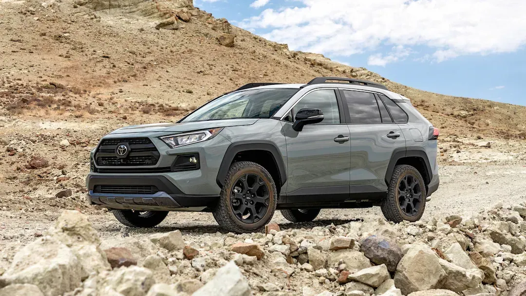 A toyota rav4 is parked on a rocky road in the desert.