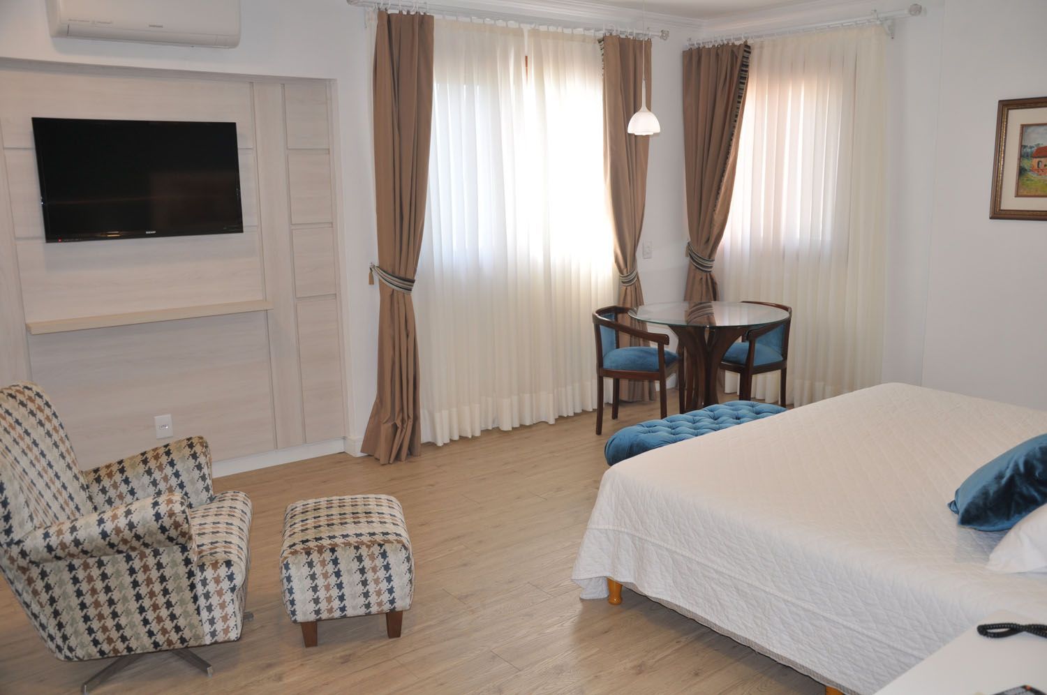 um quarto de hotel com cama, cadeira, mesa e televisão.