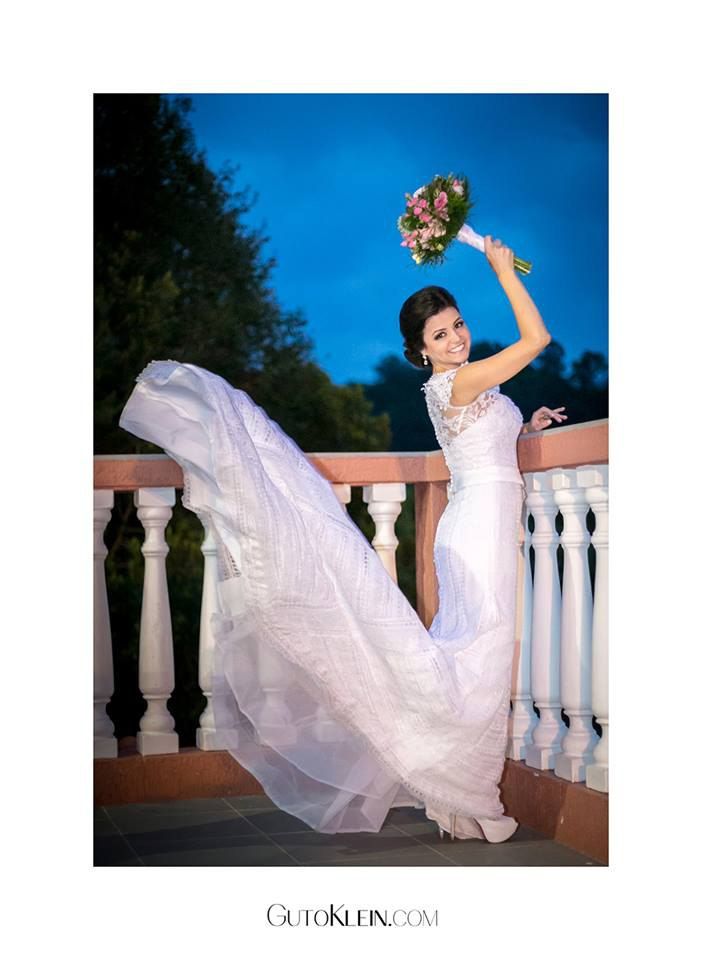 uma noiva com um vestido longo branco está segurando um buquê de flores na mão.