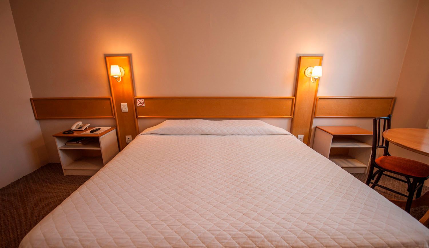 um quarto de hotel com cama, mesa, cadeira e mesa de cabeceira.