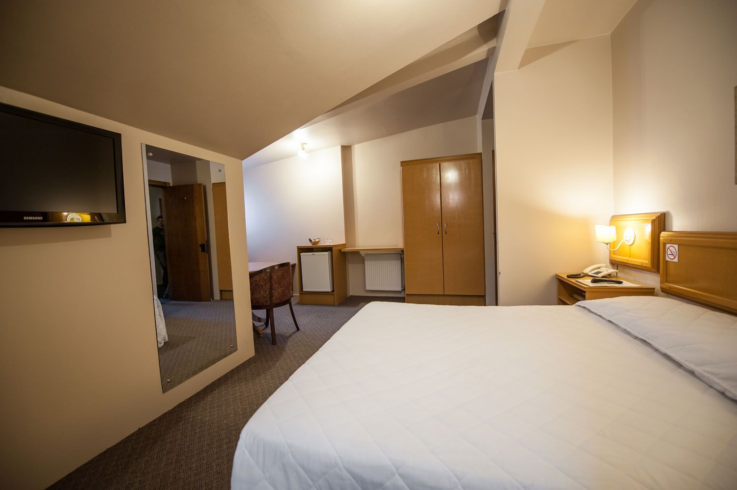 um quarto de hotel com cama, mesa, cadeira e televisão.