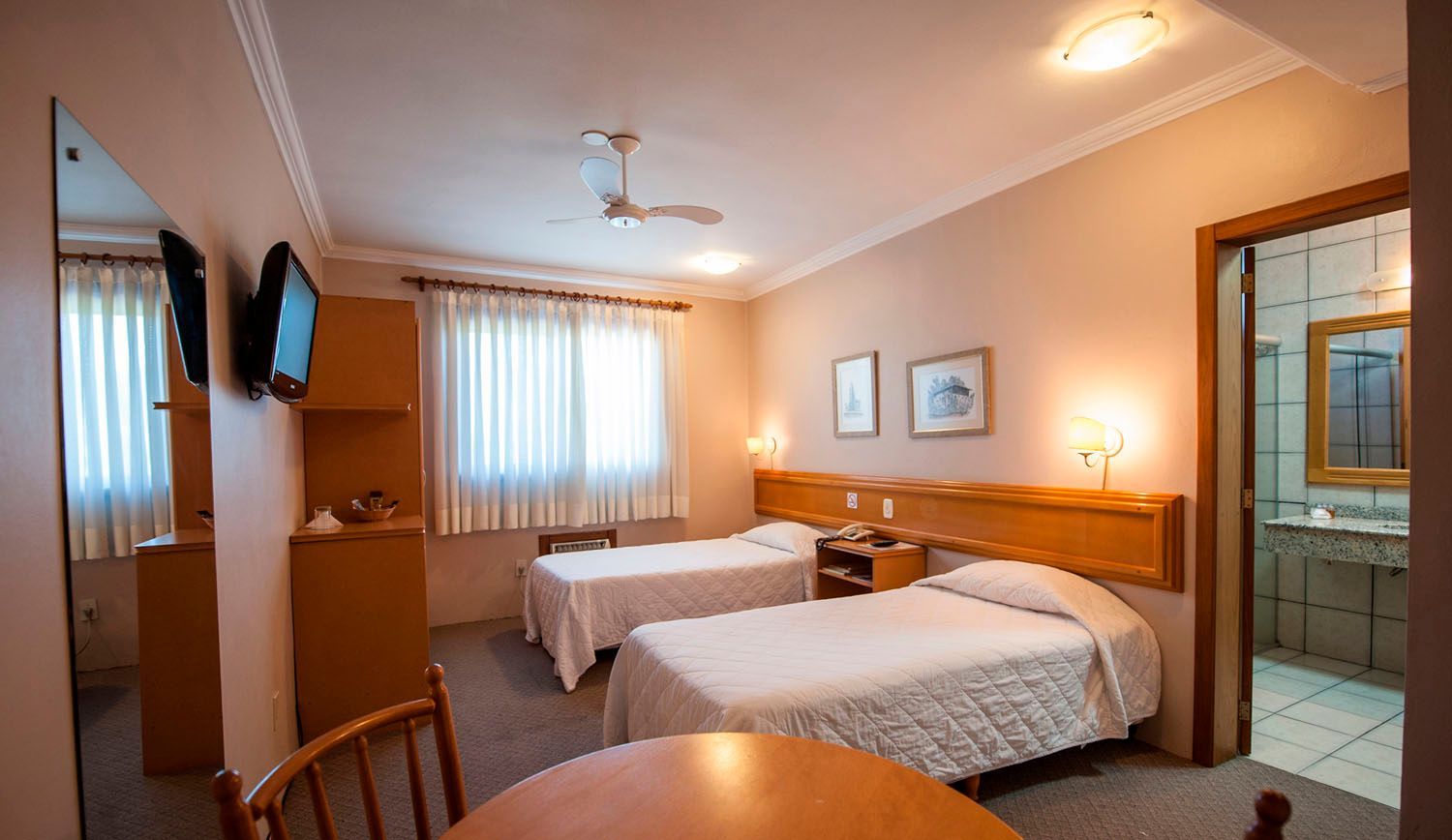 um quarto de hotel com duas camas, uma mesa e uma televisão.