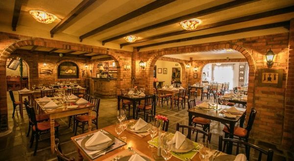 um restaurante cheio de mesas e cadeiras e uma parede de tijolos.
